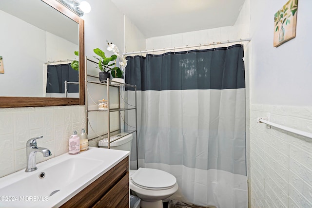 bathroom featuring walk in shower, vanity, toilet, and tile walls