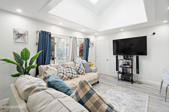 living room featuring light hardwood / wood-style flooring and lofted ceiling with skylight