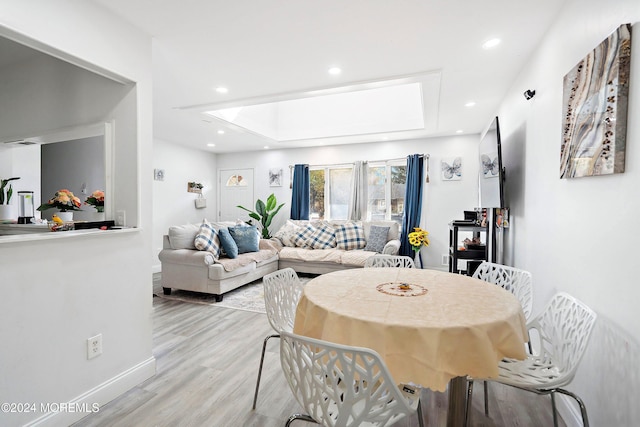 dining area featuring light wood-type flooring and a skylight