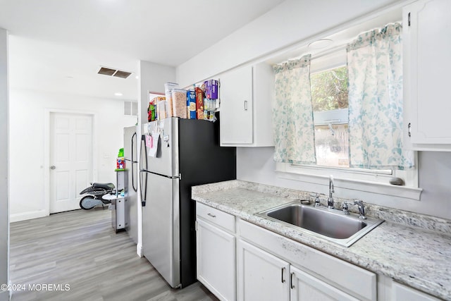 kitchen featuring white cabinets, stainless steel fridge, sink, and light hardwood / wood-style flooring