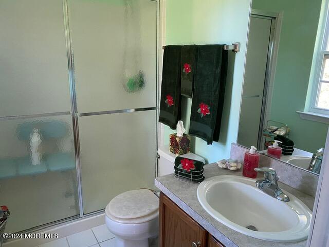 bathroom featuring vanity, toilet, an enclosed shower, and tile patterned floors