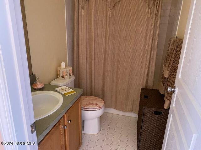 bathroom with curtained shower, vanity, and toilet