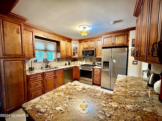 kitchen featuring tasteful backsplash, light tile patterned floors, appliances with stainless steel finishes, light stone countertops, and sink