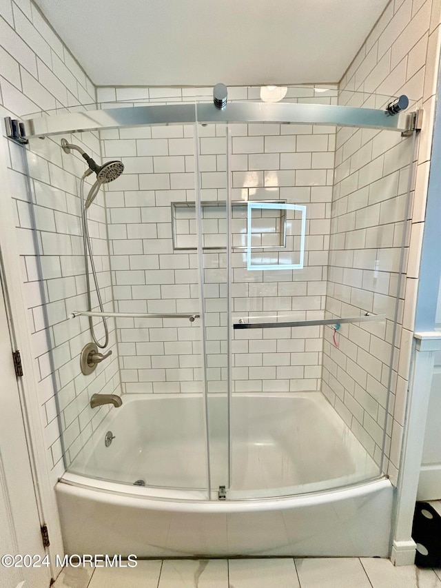 bathroom with combined bath / shower with glass door and tile patterned flooring