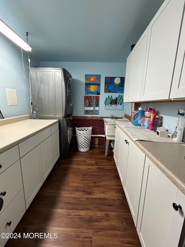 clothes washing area with stacked washer / dryer, cabinets, and dark hardwood / wood-style flooring