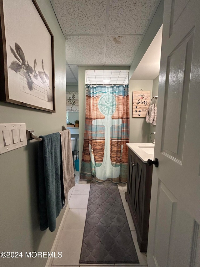 bathroom with vanity, a drop ceiling, and tile patterned floors