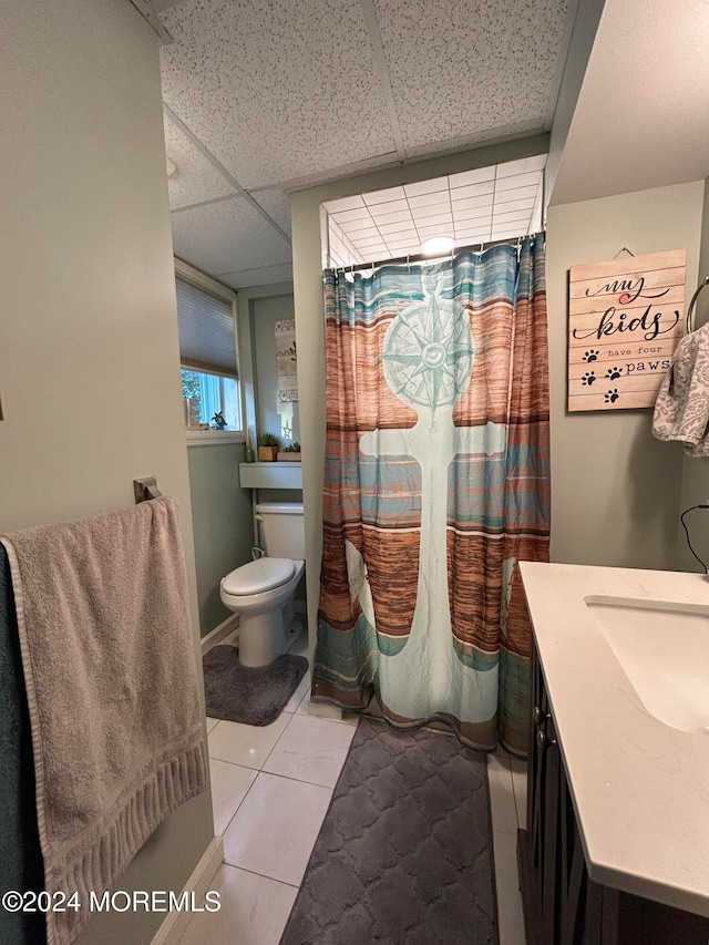 bathroom featuring toilet, a drop ceiling, vanity, and tile patterned flooring