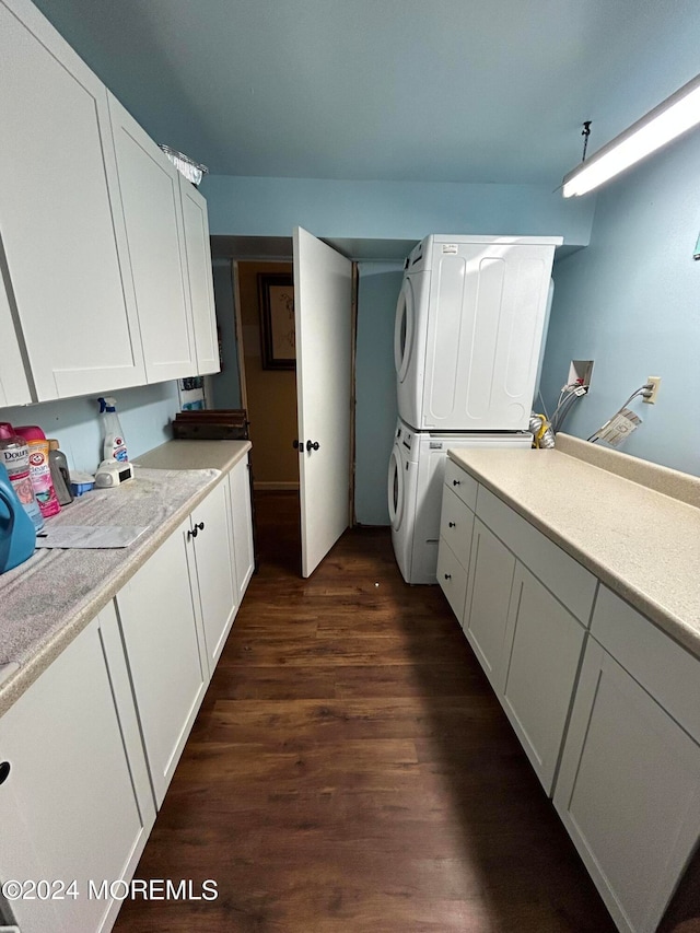 kitchen with dark wood-type flooring, stacked washer and dryer, and white cabinetry