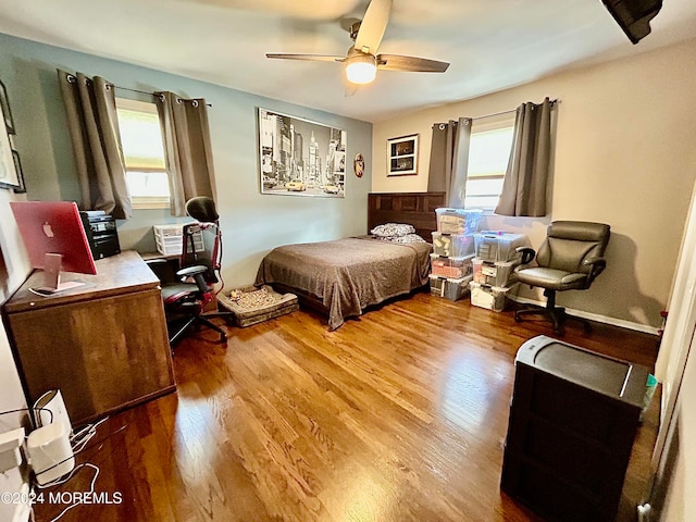 bedroom with multiple windows, wood-type flooring, and ceiling fan