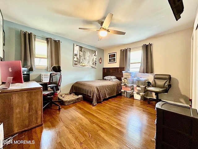 bedroom with ceiling fan, wood-type flooring, and multiple windows