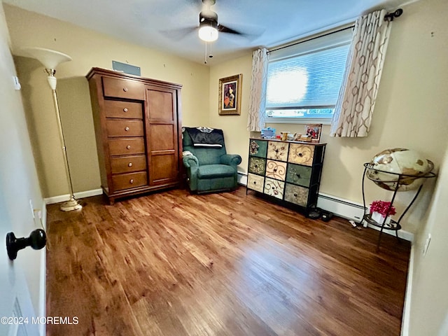 living area featuring ceiling fan, a baseboard heating unit, and hardwood / wood-style floors