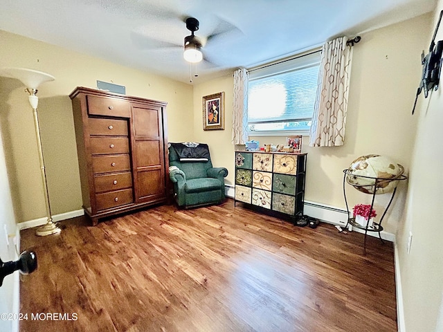 living area with baseboard heating, wood-type flooring, and ceiling fan