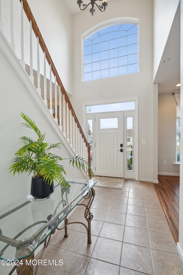 foyer featuring a towering ceiling, plenty of natural light, and light wood-type flooring