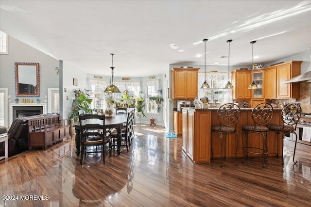 kitchen with decorative backsplash, decorative light fixtures, dark wood-type flooring, and a breakfast bar area