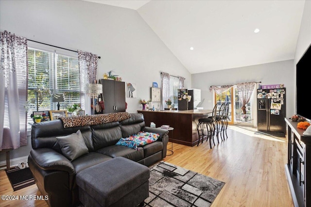 living room with high vaulted ceiling and light wood-type flooring