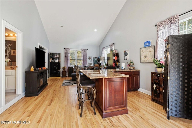 bar with high vaulted ceiling, light hardwood / wood-style flooring, and plenty of natural light