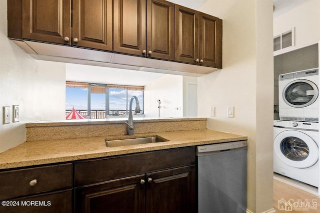kitchen with dishwasher, estacked washer and dryer, a sink, and dark brown cabinets