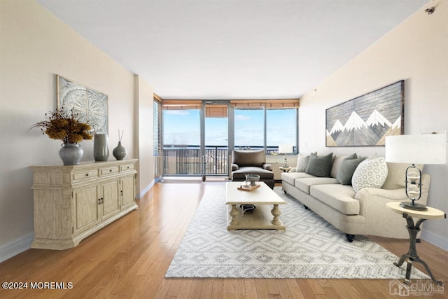 living room featuring baseboards, light wood-type flooring, and a wall of windows