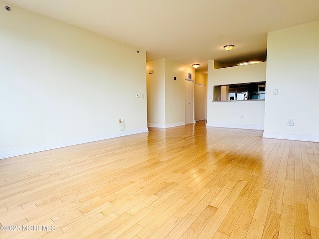 unfurnished living room with light wood finished floors and baseboards