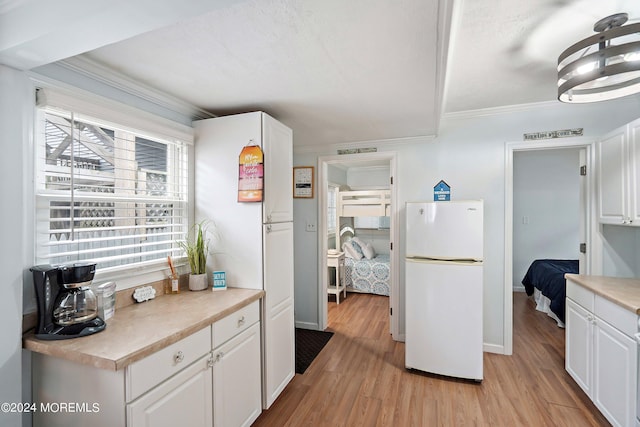 304 Bay Blvd, Seaside Heights, NJ 08751 - kitchen with freestanding refrigerator, white cabinetry, crown molding, light countertops, and light wood-style flooring