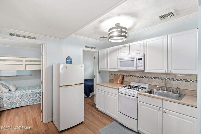 304 Bay Blvd, Seaside Heights, NJ 08751 - kitchen with white appliances, a sink, white cabinets, light wood finished floors, and backsplash
