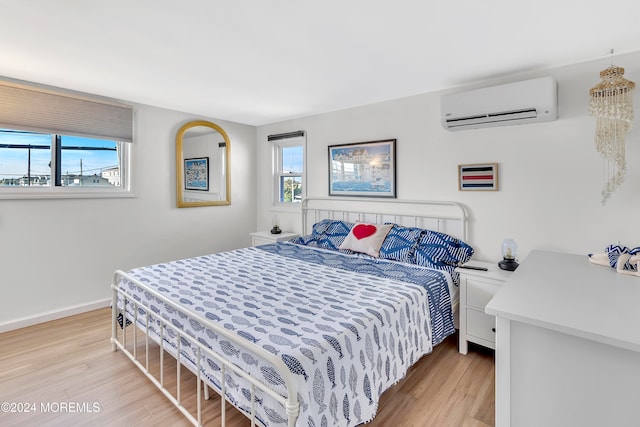 bedroom featuring light hardwood / wood-style flooring, multiple windows, and a wall mounted AC