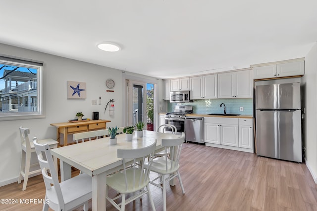 dining space featuring a wealth of natural light, sink, and light hardwood / wood-style floors