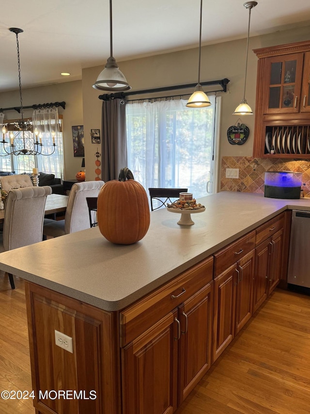 kitchen featuring dishwasher, a notable chandelier, pendant lighting, light wood-type flooring, and tasteful backsplash