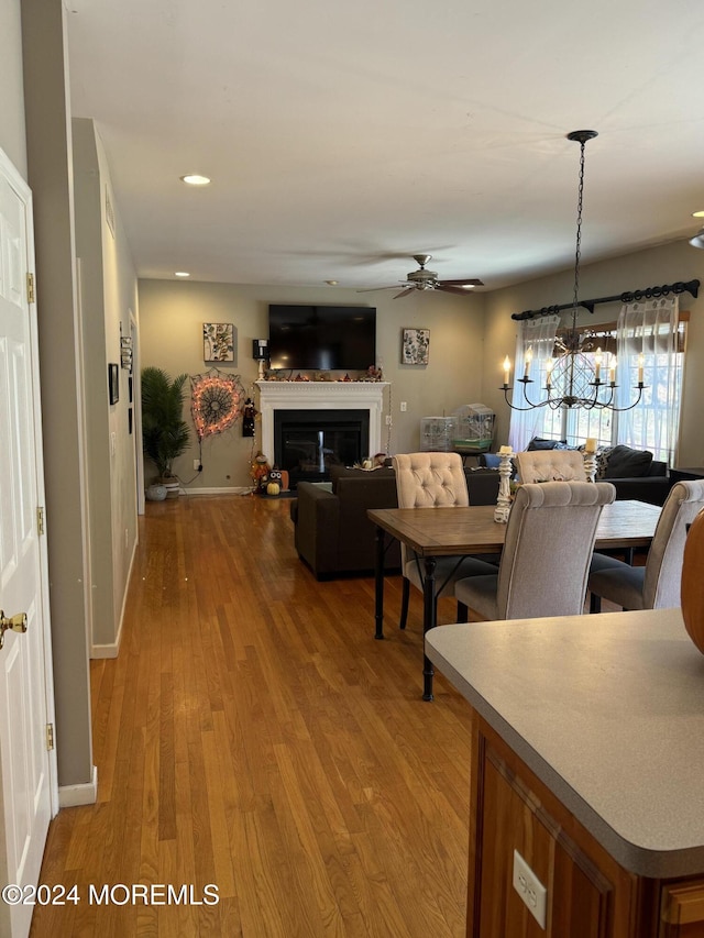 dining room featuring light wood-type flooring and ceiling fan with notable chandelier