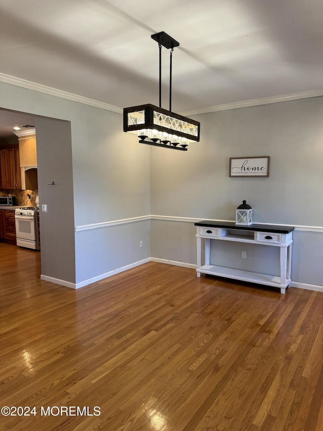 unfurnished dining area with crown molding and dark hardwood / wood-style flooring