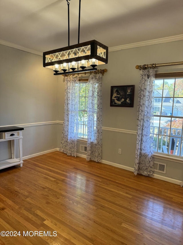 unfurnished dining area featuring crown molding and hardwood / wood-style floors