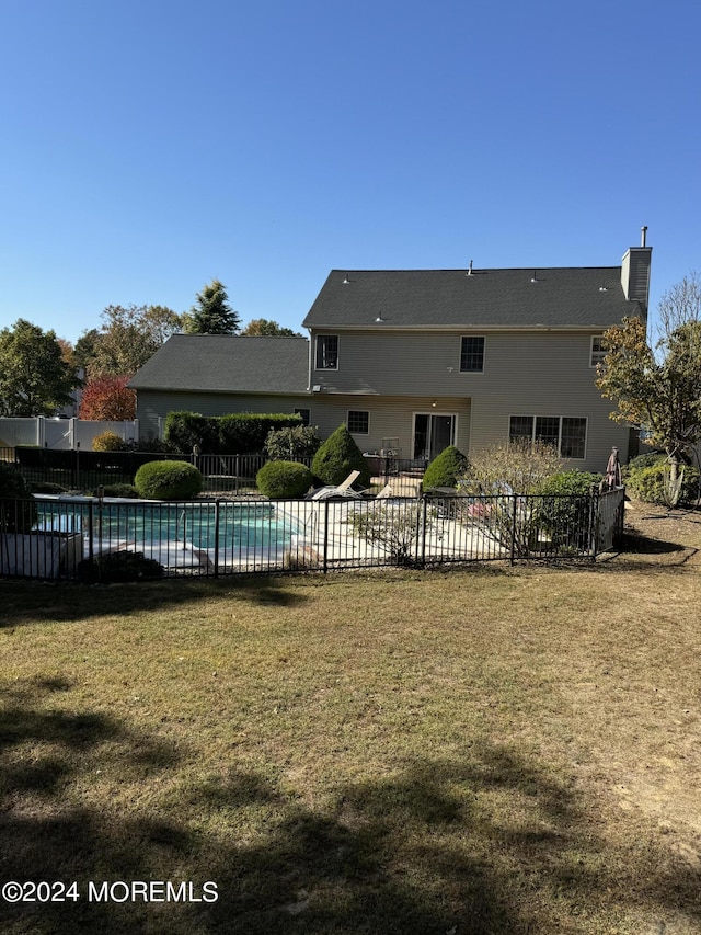 back of house featuring a yard and a fenced in pool