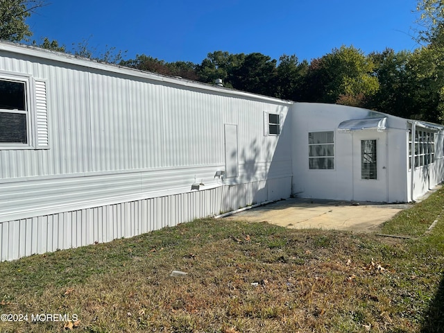 view of side of home with a yard and a patio area