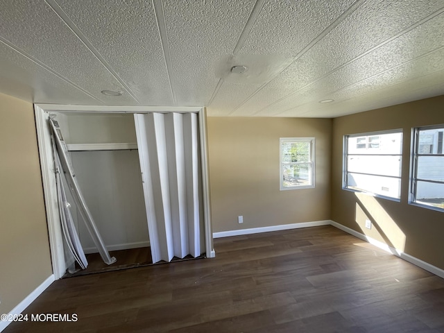 unfurnished room featuring a textured ceiling and dark hardwood / wood-style floors