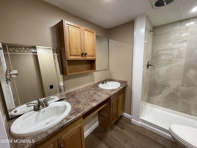 bathroom featuring vanity, toilet, tiled shower, and hardwood / wood-style floors