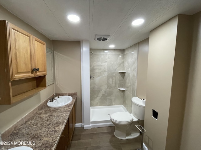 bathroom featuring vanity, a tile shower, and toilet