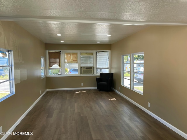 interior space featuring a textured ceiling, cooling unit, a wealth of natural light, and dark hardwood / wood-style floors