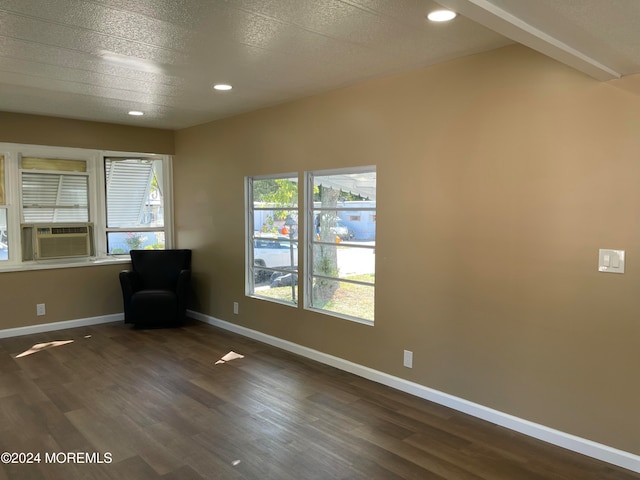 empty room featuring cooling unit, a textured ceiling, and dark hardwood / wood-style floors