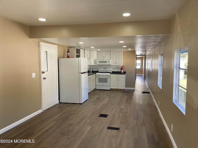 kitchen with dark wood-type flooring, white cabinets, and white appliances