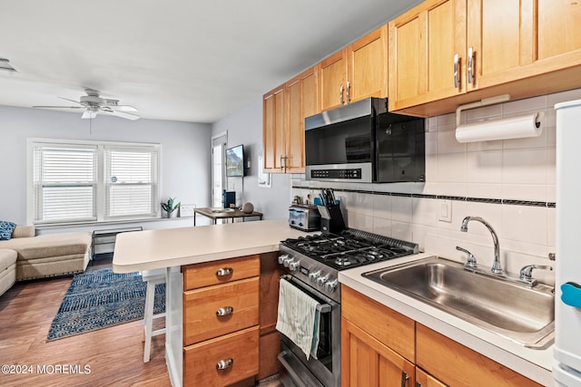 kitchen with sink, a kitchen bar, backsplash, stainless steel appliances, and dark hardwood / wood-style floors