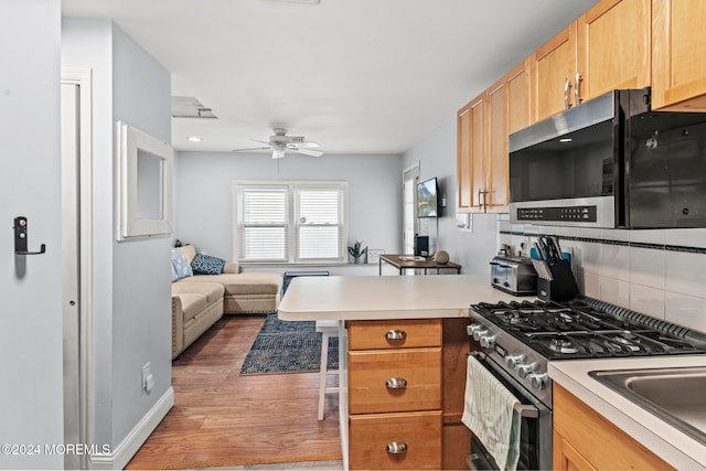 kitchen featuring kitchen peninsula, tasteful backsplash, dark hardwood / wood-style flooring, appliances with stainless steel finishes, and a breakfast bar area