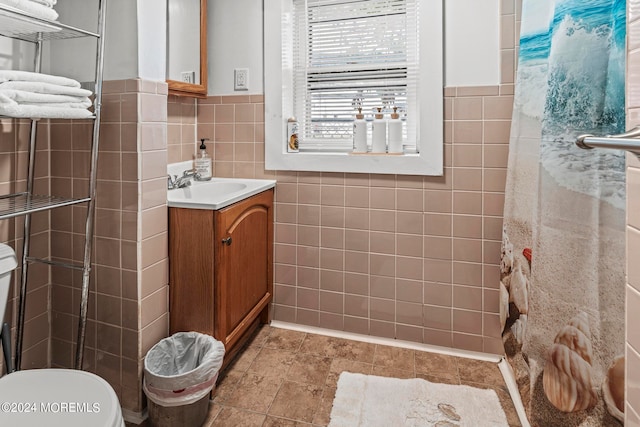 bathroom with toilet, a shower with shower curtain, vanity, and tile walls