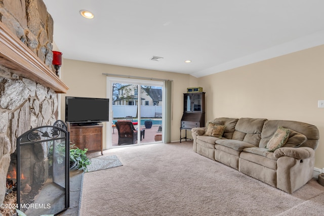 carpeted living room with a stone fireplace