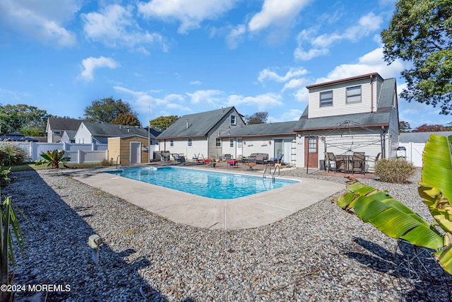 view of swimming pool with a patio and a storage shed