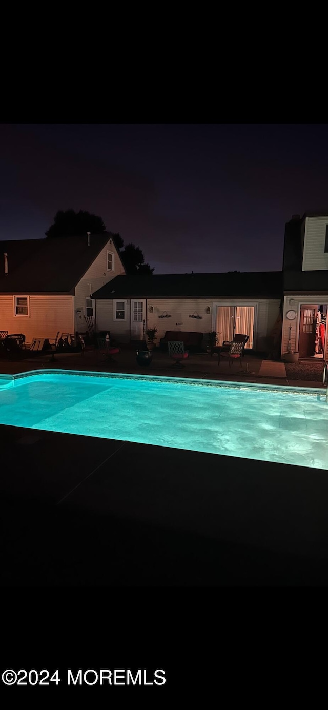 pool at twilight featuring a patio area