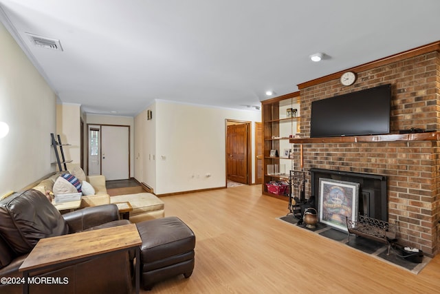 living room featuring light hardwood / wood-style floors, crown molding, and a brick fireplace