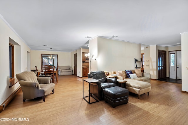 living room featuring light hardwood / wood-style flooring, an inviting chandelier, and ornamental molding