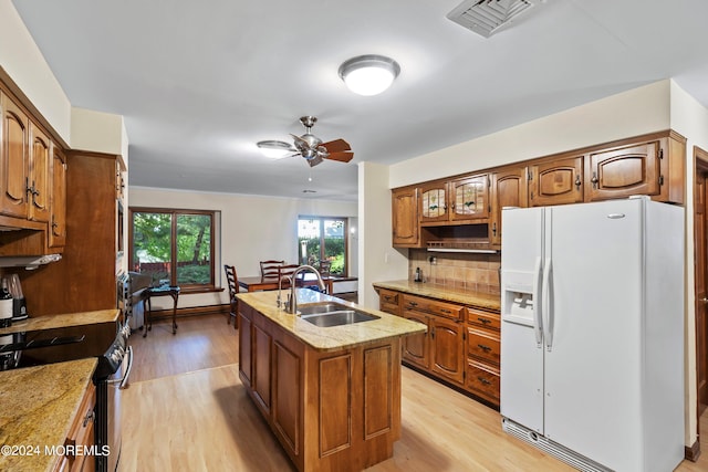 kitchen featuring light hardwood / wood-style flooring, a center island with sink, sink, stainless steel electric range, and white refrigerator with ice dispenser