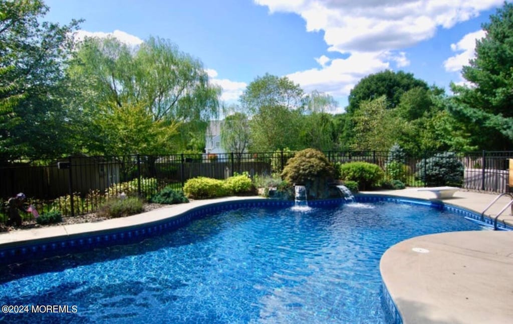 view of swimming pool featuring pool water feature and a diving board