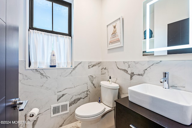 bathroom with vanity, tile walls, and toilet